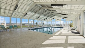 Ein Hallenbad mit hoher Decke, großen Fenstern und Blick auf die Stadtlandschaft.
