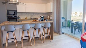 A modern kitchen with a central island, bar stools, a built-in oven, and a view of the outdoor patio.