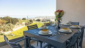 A dining table set for four with plates, cutlery, and wine glasses, overlooking a scenic landscape.