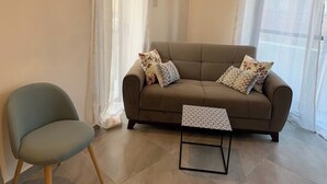 A living room with a sofa, a chair, and a small table. - This apartment is a 1 bedroom(s), 1 bathrooms, located in Tas-Sliema, null. (Tas-Sliema)