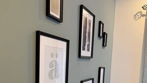 A wall with multiple framed artworks, a light switch, and a wooden table with a chair. - This apartment is a 1 bedroom(s), 1 bathrooms, located in Tas-Sliema, null. (Tas-Sliema)