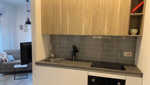 A modern kitchen with grey tiled backsplash, wooden cabinets, a black oven, and a grey countertop. - This apartment is a 1 bedroom(s), 1 bathrooms, located in Tas-Sliema, null. (Tas-Sliema)