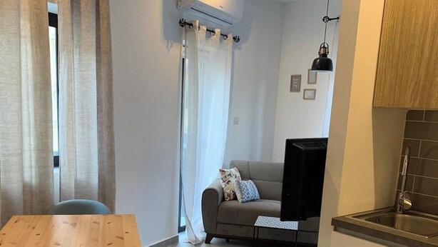 A modern kitchen with a built-in sink and a dining area with a wooden table and a single chair. - This apartment is a 1 bedroom(s), 1 bathrooms, located in Tas-Sliema, null. (Tas-Sliema)