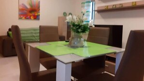 Un comedor con una mesa, sillas, un florero con flores y un cuadro de colores en la pared.
