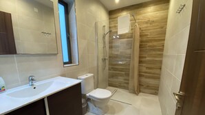 Un baño moderno con lavamanos, inodoro y ducha blancos.