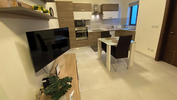 Una cocina moderna con un televisor de pantalla plana, una mesa de comedor con sillas y una planta en maceta.