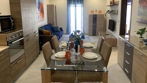 A modern kitchen with a dining area, featuring a glass table, wooden cabinets, and a built-in oven.