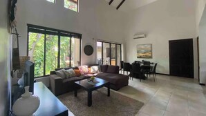 A spacious living room with a sectional sofa, a coffee table, and a dining area with chairs and a table.