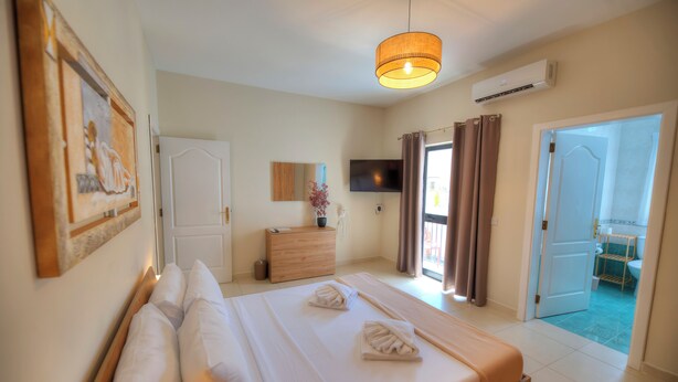Habitación de hotel con una cama grande, una mesita de noche, un televisor y vistas al exterior.