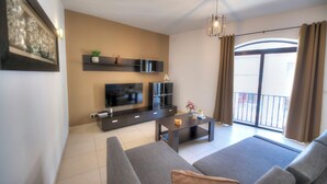 Una sala de estar moderna con una televisión de pantalla plana, un sofá, una mesa de centro y un balcón con cortinas.