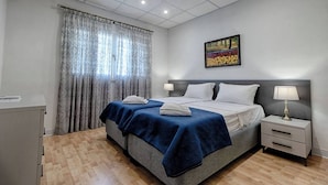 A bedroom with a bed, bedside tables, a desk, and a painting on the wall.
