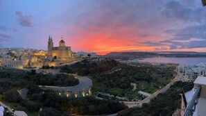 A historic cityscape with a prominent cathedral, a roundabout, and a coastal view during sunset. - Relax with the whole family at this peaceful place to stay (Il-Mellieħa)