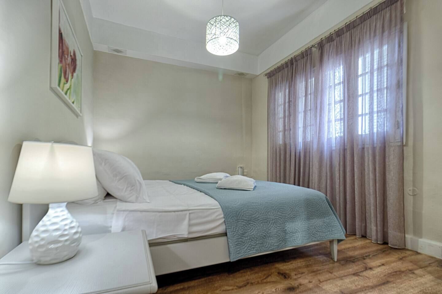 A bedroom with a bed, a bedside table, a lamp, and a window with curtains.