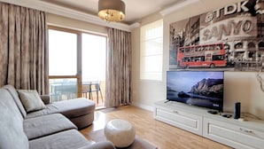A modern living room with a grey sofa, a flat-screen TV, and a wall-mounted artwork of a red double-decker bus.