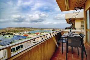 A balcony with a table set for dining, overlooking a solar farm and a body of water. - Relax with the whole family at this peaceful place to stay (Il-Mellieħa)