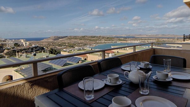 A dining table set on a balcony with solar panels in the background.