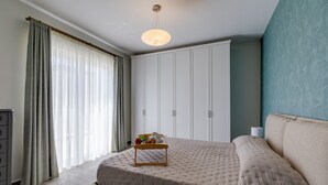 Ein Schlafzimmer mit einem Bett, einem Nachttisch mit Tablett, einem Kleiderschrank und einem Fenster mit Vorhängen.