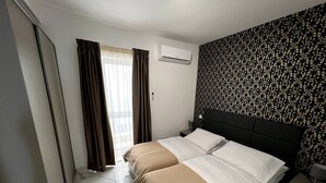 Ein Hotelzimmer mit Bett, Nachttisch, Klimaanlage und einer Wand mit Muster.