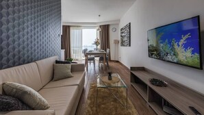 A modern living room with a sofa, coffee table, TV, and a dining area with a table and chairs. - Kick back and relax in this calm, stylish space (San Pawl il-Baħar)