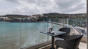 A balcony with a table and chairs overlooking a coastal town. - Kick back and relax in this calm, stylish space (San Pawl il-Baħar)