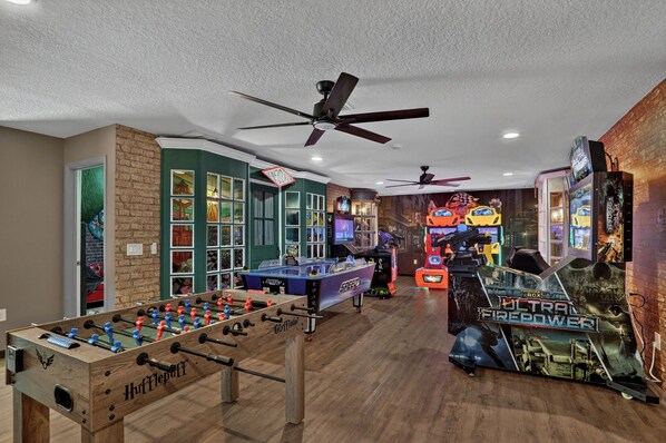 Une pièce équipée d’un baby-foot, d’une table de billard et de jeux d’arcade.
