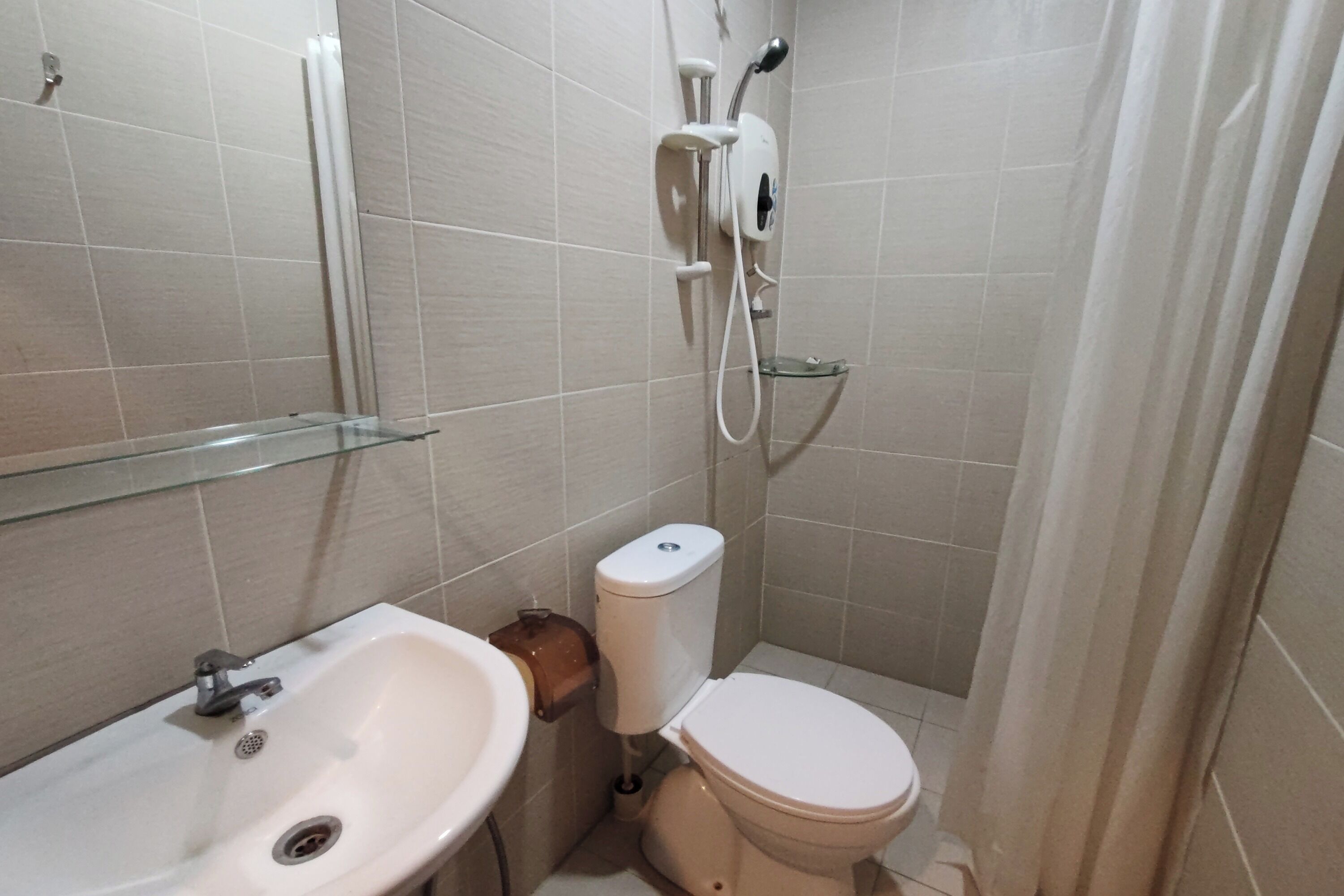 A small bathroom with a sink, toilet, and shower.