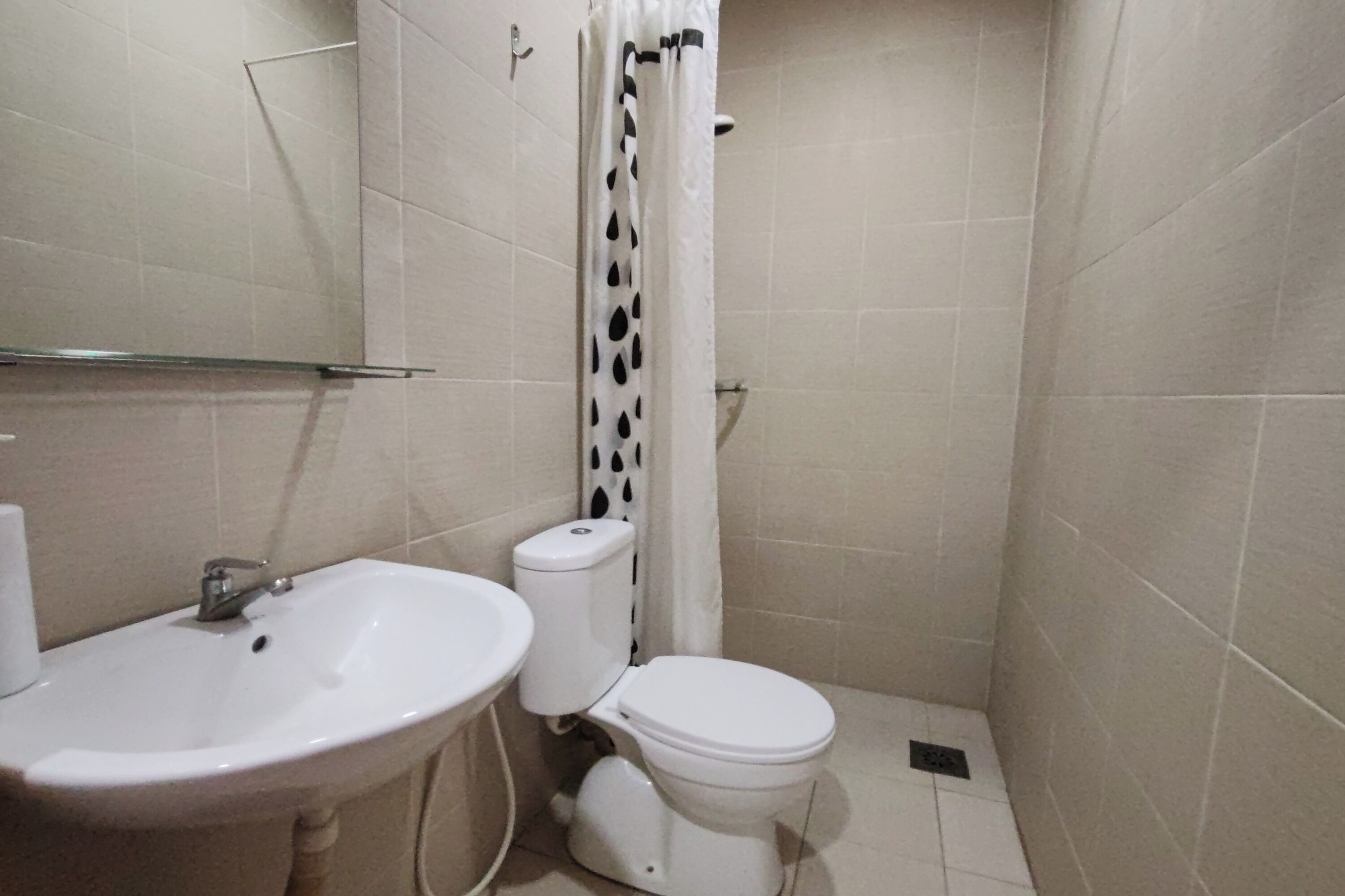 Een kleine badkamer met een wit wastafel, toilet en douchegordijn.
