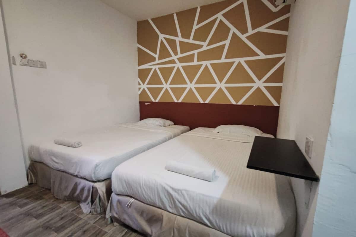 A room with two single beds, a geometric patterned headboard, a small black shelf, and a wooden floor.