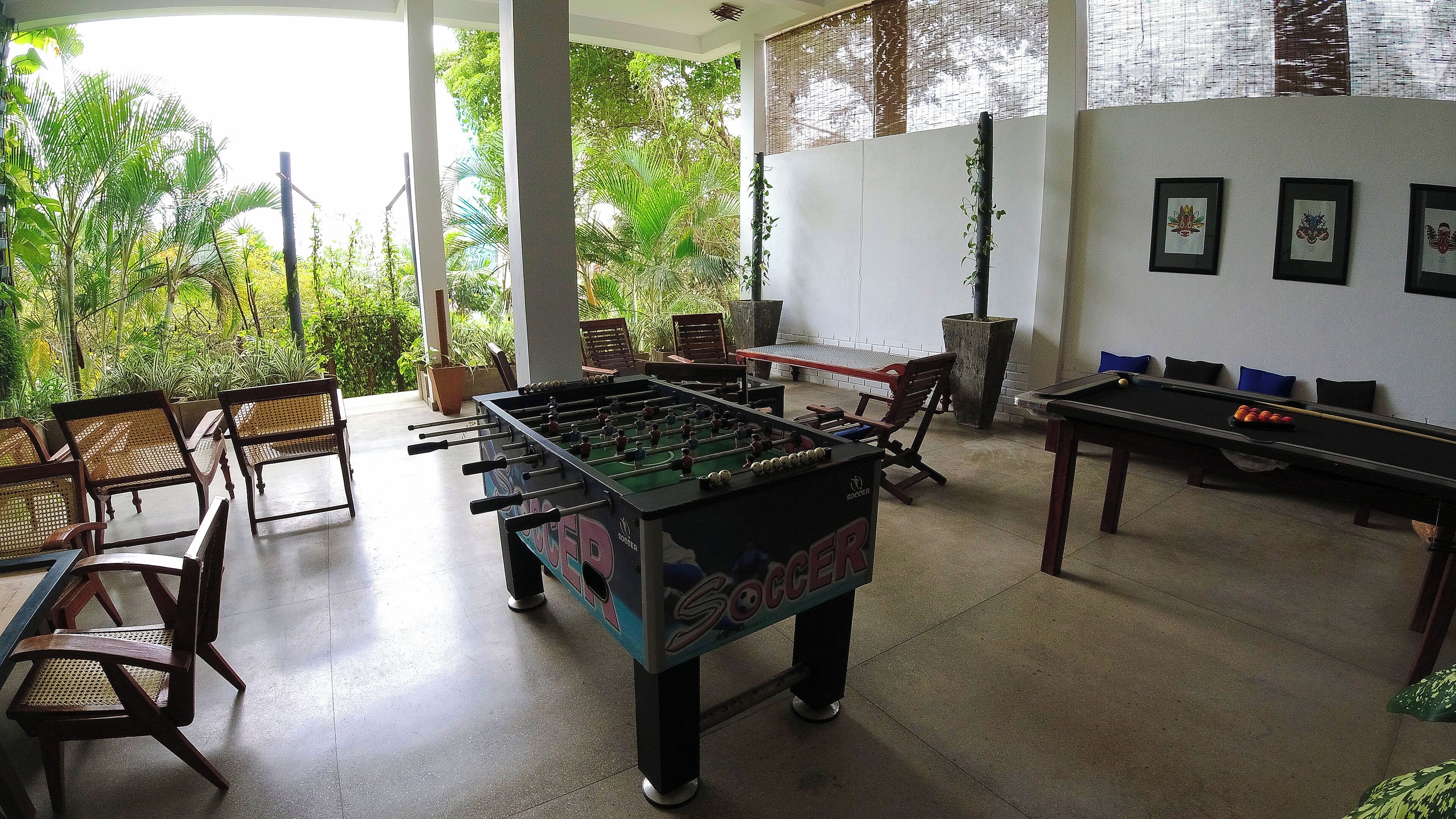 A room with a foosball table, a pool table, and several chairs.