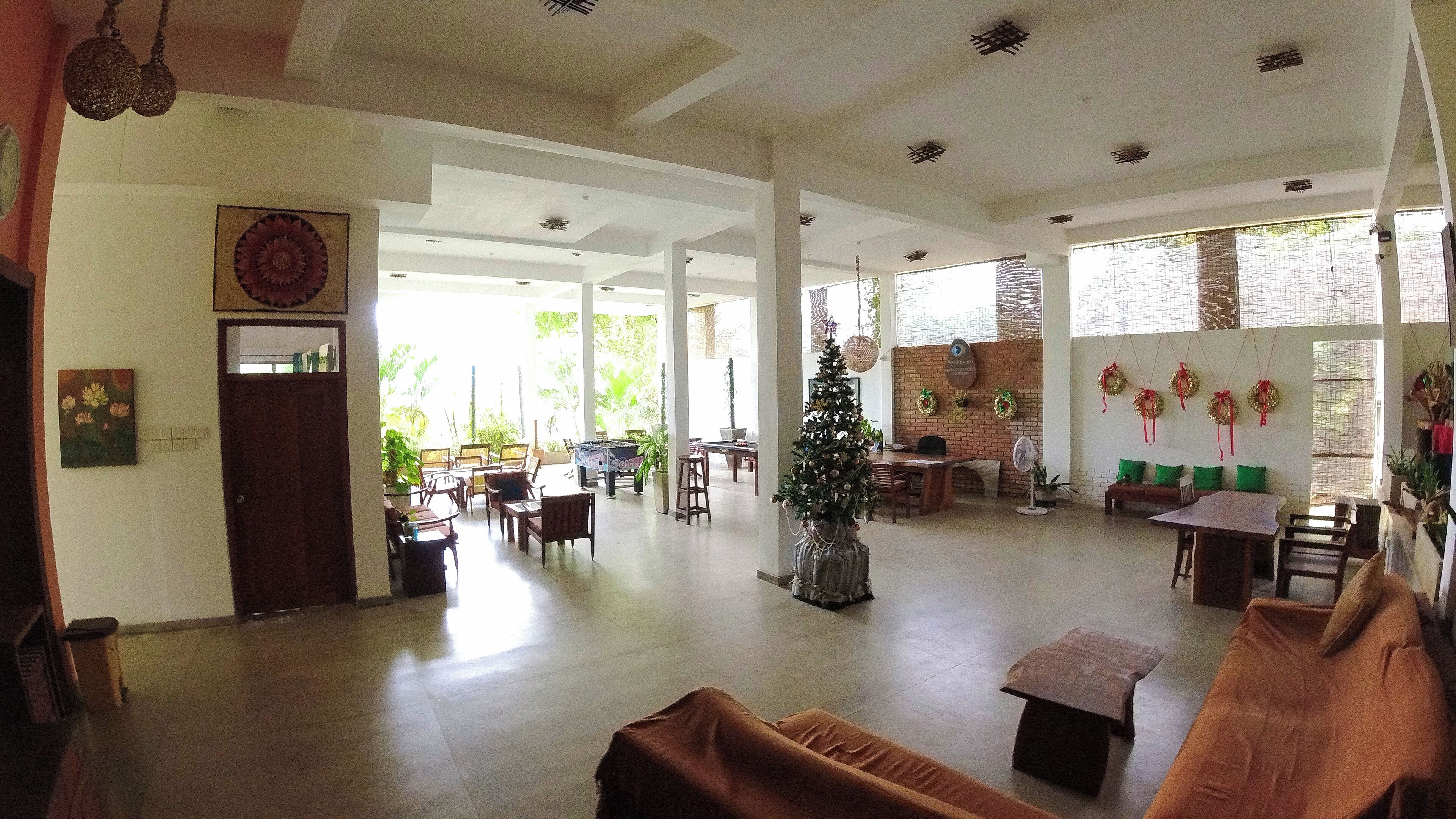 A spacious indoor area with high ceilings, a Christmas tree, and a dining area with tables and chairs.