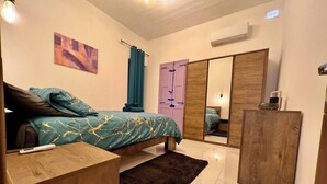 A modern bedroom with a bed, a wooden nightstand, a mirror, and a wardrobe.