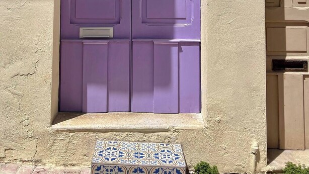 A purple door with a number plate '54' and a decorative metal crest above it.