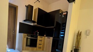 A modern kitchen with a built-in oven, a black refrigerator, and wooden cabinets.