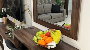 Een moderne woonkamer met een houten bureau, een schaal met fruit, een televisie en een bank.