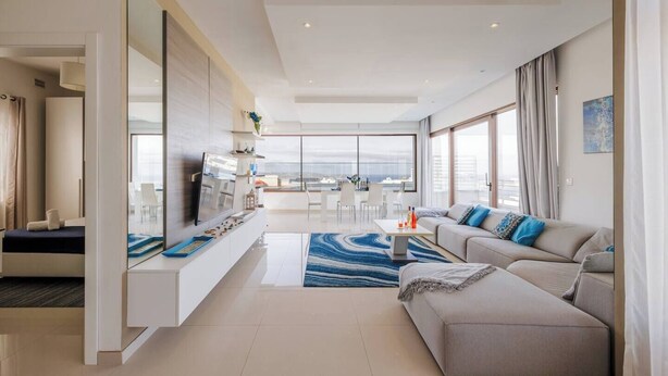 A modern living room with a sofa, TV, and a dining area with a view.