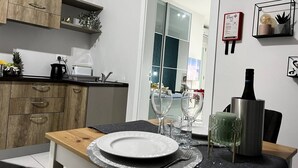 Una cocina moderna con armarios de madera, encimera negra y una zona de comedor con una mesa preparada para dos.