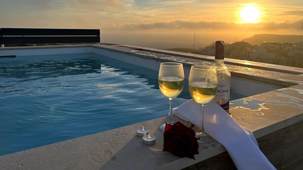 A rooftop pool with two glasses of white wine and a bottle, a rose, and candles. - Take it easy and soak up the good life at this unique luxury penthouse, where sweeping sea views and your own rooftop pool make every moment feel unforgettable. (Il-Mellieħa)