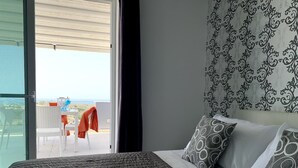 A bedroom with a large bed, a patterned headboard, and a view of a balcony with outdoor furniture. - Take it easy and soak up the good life at this unique luxury penthouse, where sweeping sea views and your own rooftop pool make every moment feel unforgettable. (Il-Mellieħa)