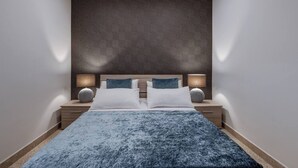A modern hotel room with a large bed, two bedside tables with lamps, and a patterned wall.
