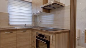 A modern kitchen with wooden cabinetry, a built-in oven, and a stainless steel range hood. - This apartment is a 2 bedroom(s), 1 bathrooms, located in Il-Mellieħa, null. (Il-Mellieħa)