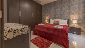 Ein Schlafzimmer mit einem großen Bett, einem dunklen Holzschrank und einer strukturierten Wand.