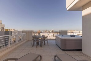 Une terrasse sur le toit avec une table et des chaises, un jacuzzi et une vue sur le paysage urbain.