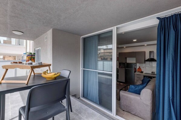Un apartamento moderno con balcón, comedor y kitchenette.