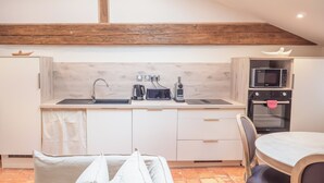 A kitchen with a wooden beam ceiling, a sink, a microwave, and an oven. - Le Cadran Solaire, Gîte Intimiste Haut de Gamme Avec Piscine et Sauna, à Pézenas (Pézenas)