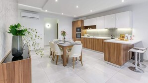 A modern kitchen with white cabinets, a wooden island, and a dining area with a table and chairs.
