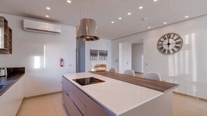 Une cuisine moderne dotée d’un îlot central, d’un éclairage encastré au plafond, d’une horloge murale et d’un extincteur.