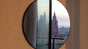 Un miroir rond reflétant un bâtiment doté d’une tour horloge, qui pourrait être un monument historique ou un lieu d’importance particulière.