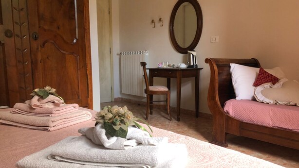 Une chambre à coucher avec un lit, un bureau, une chaise et une salle de bain visible à travers une porte ouverte.