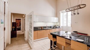 A modern kitchen with white cabinets, a granite countertop, and a hanging pot rack.