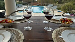 A dining table with two wine glasses, plates, and bowls of fruit, overlooking a swimming pool. - "Nuova Villa Ulivo" among olive and almond trees with private swimming pool (Carovigno)